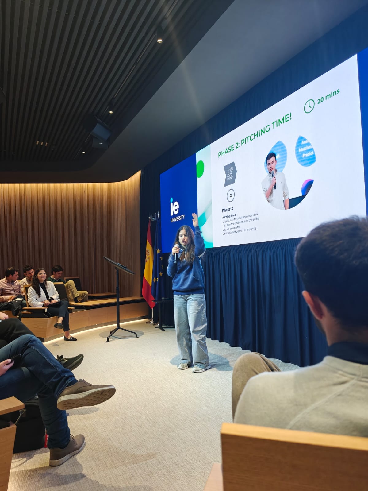 Manvi pitching with a microphone on stage at IE University