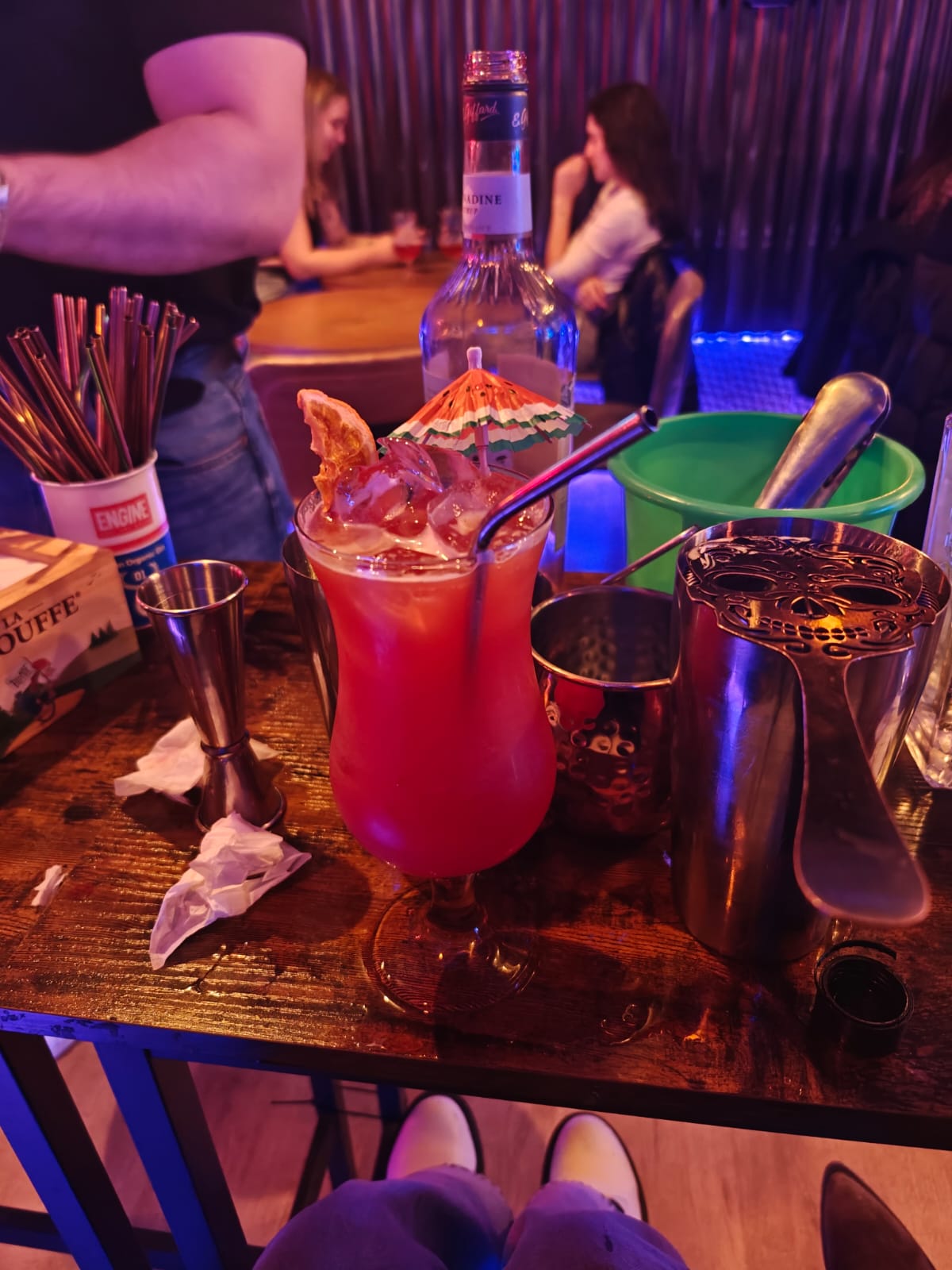 A bright red tropical cocktail with an umbrella on a bar counter